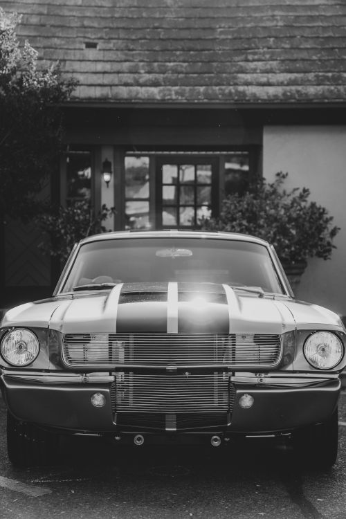 Free Black and white image of a classic Ford Mustang parked in front of a quaint building in Solvang, CA. Stock Photo