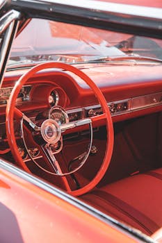 Classic red car interior featuring a vintage steering wheel and dashboard design.