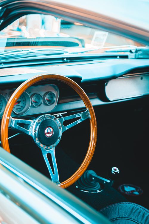 Free Close-up photo of a vintage car interior featuring a wooden steering wheel and classic design elements. Stock Photo