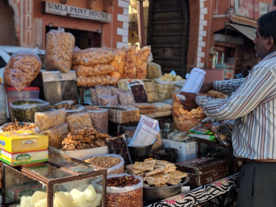Top 15 Must-Try Street Foods in Ahmedabad and Where to Find Them 1 A street food vendor at a traditional Indian stall serving freshly made snacks to customers at a busy market.