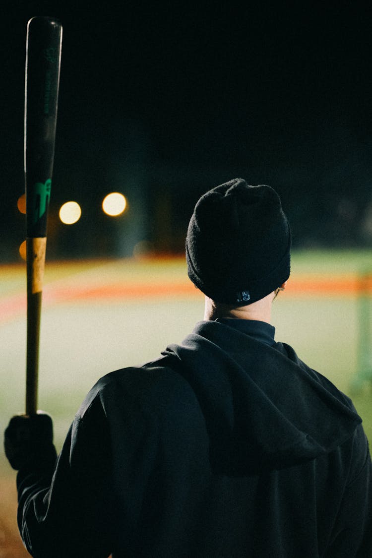 Back View Of A Man Wearing Black Beanie Hat Holding A Baseball Bat 