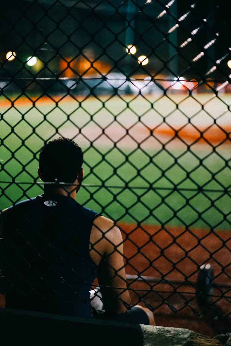 Back Of A Sitting Man Through A Fence