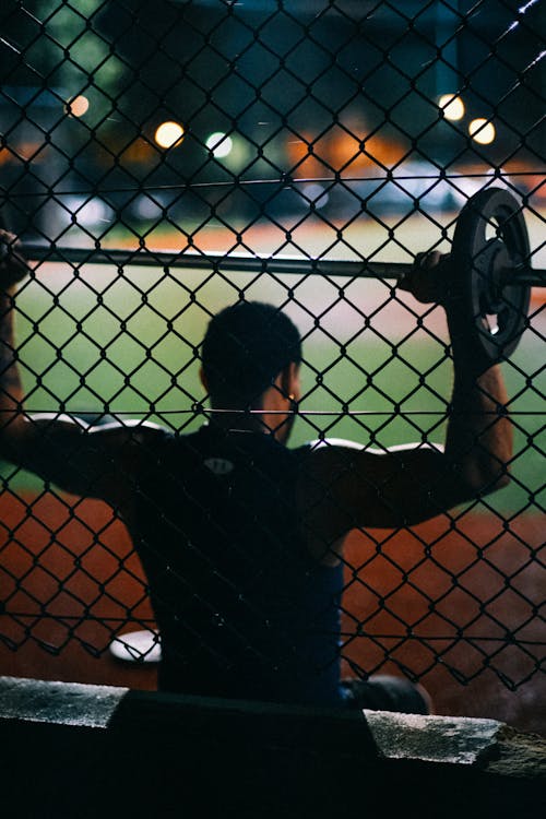 Man in Black Lifting Weights in a Sports Field