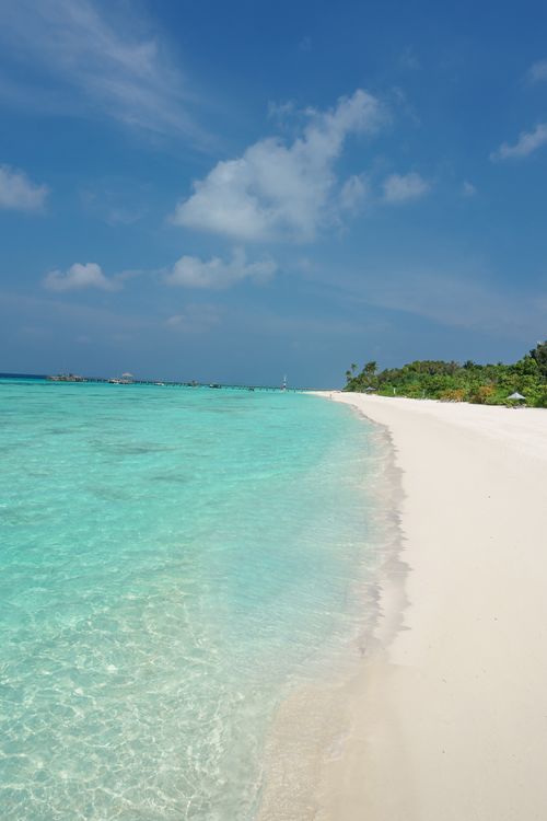 Free A serene tropical beach with turquoise water, white sand, and a clear blue sky, perfect for summer travel. Stock Photo