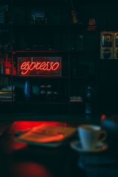 A warm and inviting coffee shop interior illuminated by a vibrant neon espresso sign.