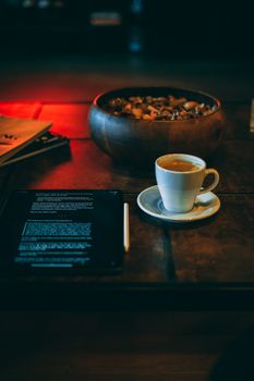 A warm coffee break setup with a cappuccino, tablet, and bowl on a rustic table.