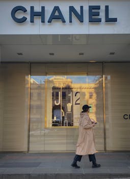 Elegant woman walks by a luxury Chanel storefront, capturing urban fashion vibes.