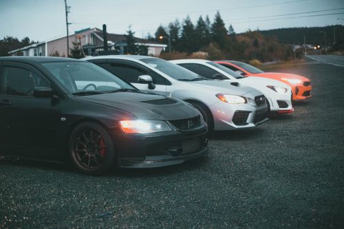 Free Four sporty cars parked on a rural roadside at twilight, showcasing modern automotive design. Stock Photo