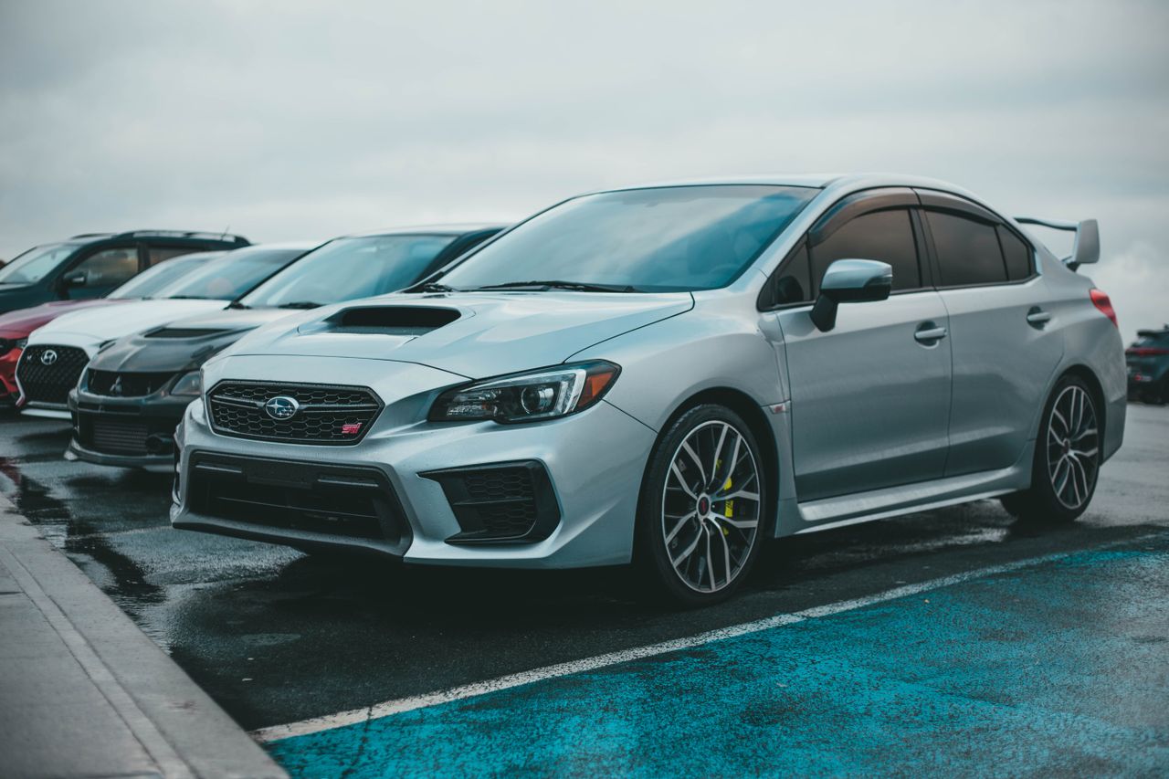 a silver subaru wrx parked in a city parking lot with other cars on a