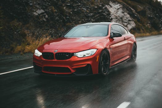 Dynamic red BMW sports car driving on a wet road, perfect for illustrating luxury and speed.