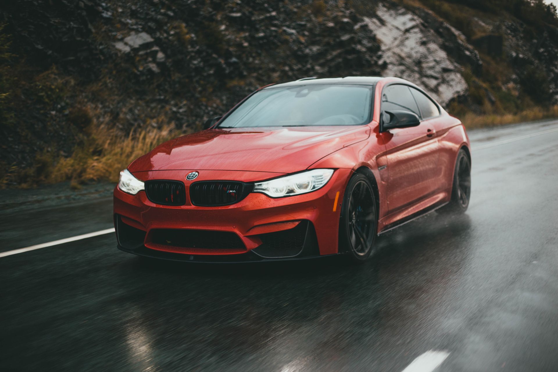 Raudonas BMW M4 važiuoja šlapiu keliu