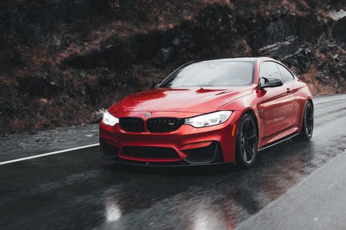 Free A vibrant red sports car driving on a wet road, showcasing speed and elegance. Stock Photo