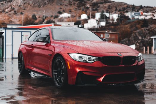 Red sports car parked on a wet urban street, showcasing luxury automotive design after rain.