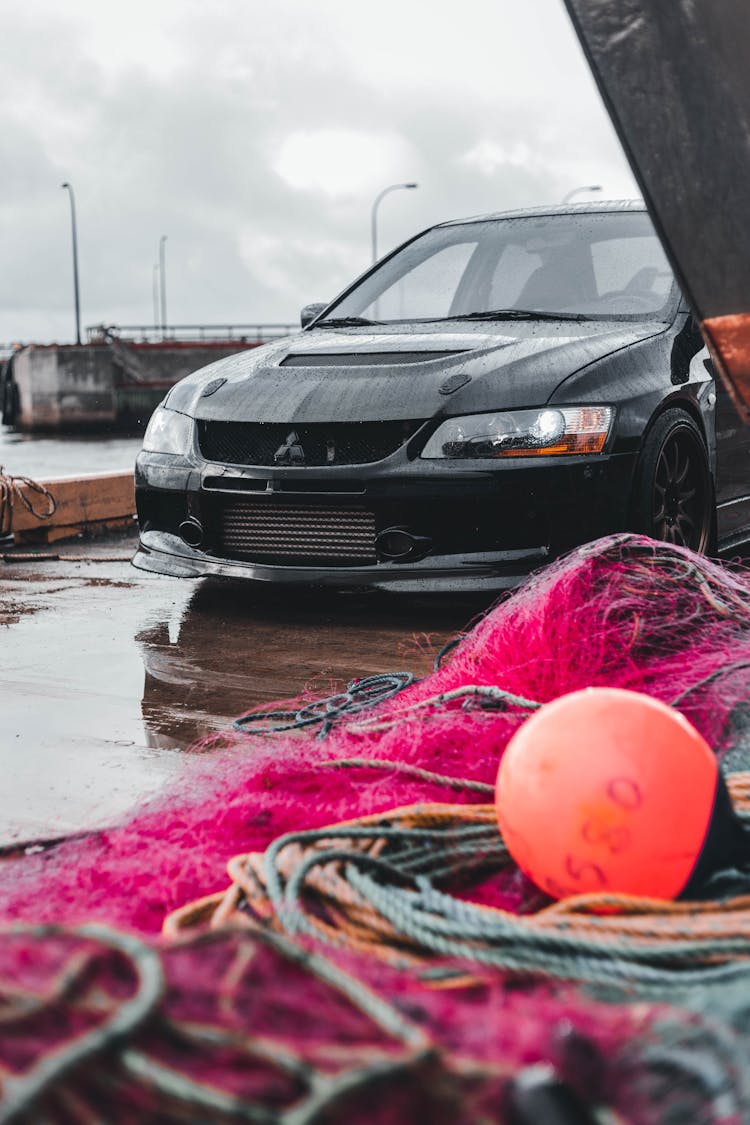 Car Parked On A Pier By A Pile Of Nets