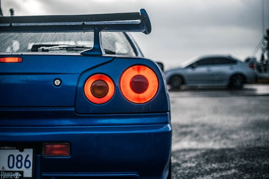 Dynamic close-up of a blue sports car's illuminated taillight in an outdoor setting, evoking speed and style.
