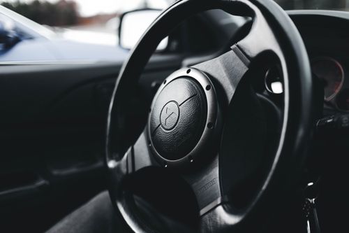 Free Detailed view of a car steering wheel, highlighting modern vehicle interior design. Stock Photo