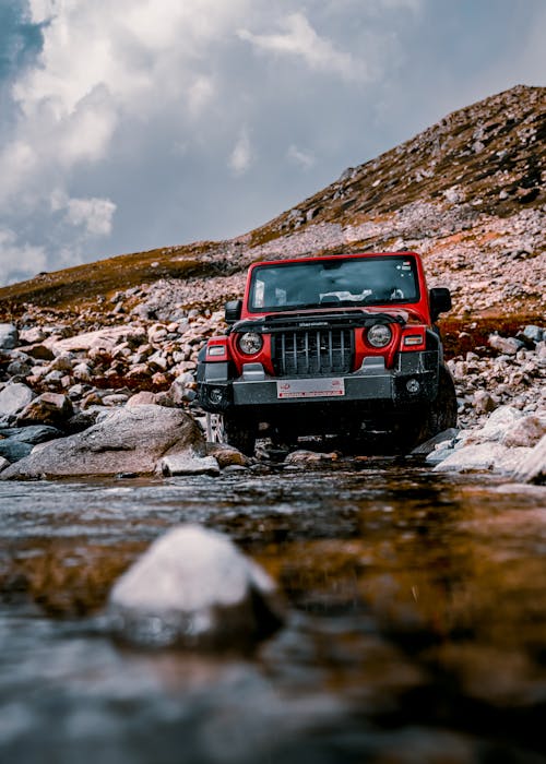 Red Mahindra Thar 4x4 Car Parked by the Rocky River Bank