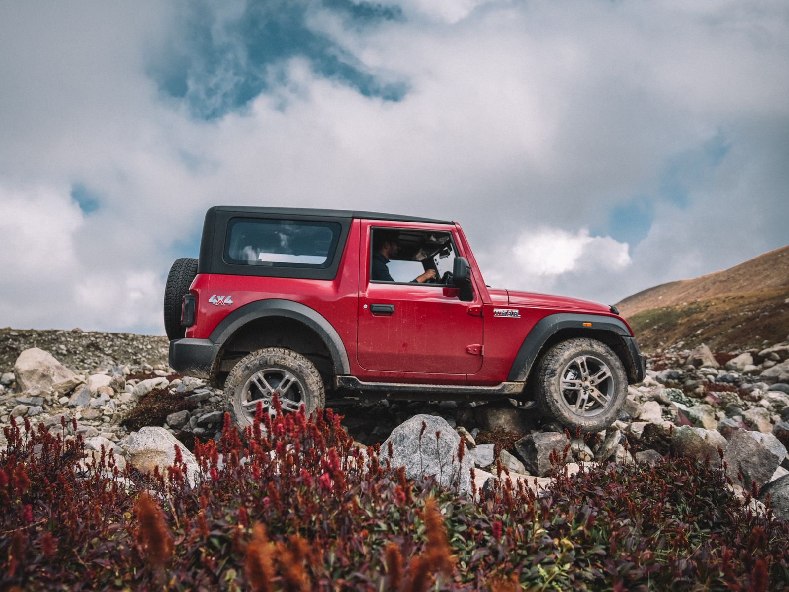 Red 4x4 SUV parked on rocky mountain terrain during an off-road trip