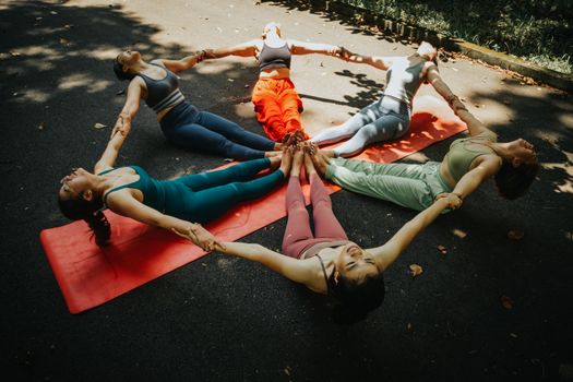 A group of women performing yoga outdoors in a circle, showcasing unity and fitness.