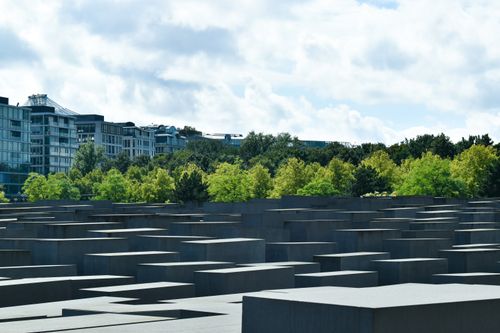 Free View of the Holocaust Memorial in Berlin with a backdrop of trees and a cloudy sky. Stock Photo