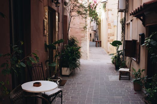 Picturesque alleyway in Chania with plants and outdoor seating, capturing the charm of Greek architecture.