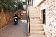 在希腊哈尼亚的一条古色古香的小巷里，一名摩托车手和一只猫正在石楼梯上休息