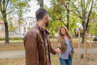 一对夫妇在美丽的秋日公园里手牵着手，悠闲地散步，分享着幸福的时光