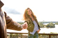 一位女士在风景秀丽的户外露台上与某人牵手微笑