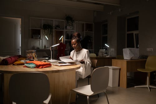 Young African American fashion designer working late in sewing work space