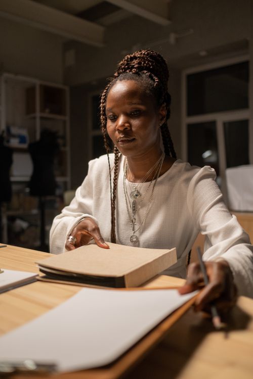 Free A focused fashion designer working late in a dimly lit studio. Stock Photo