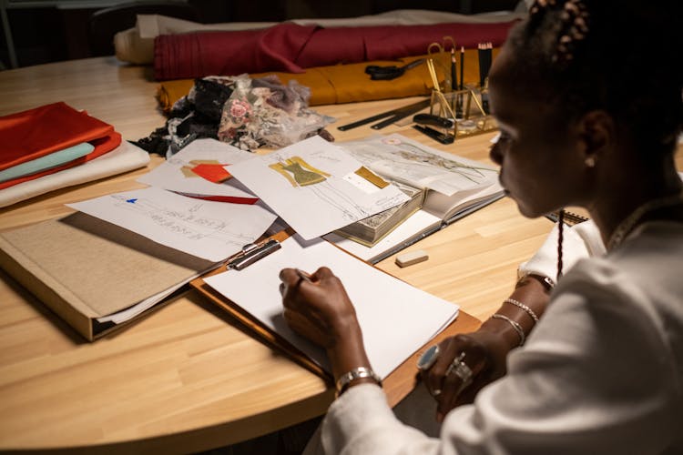 Fashion Designer Working On Large, Cluttered Desk