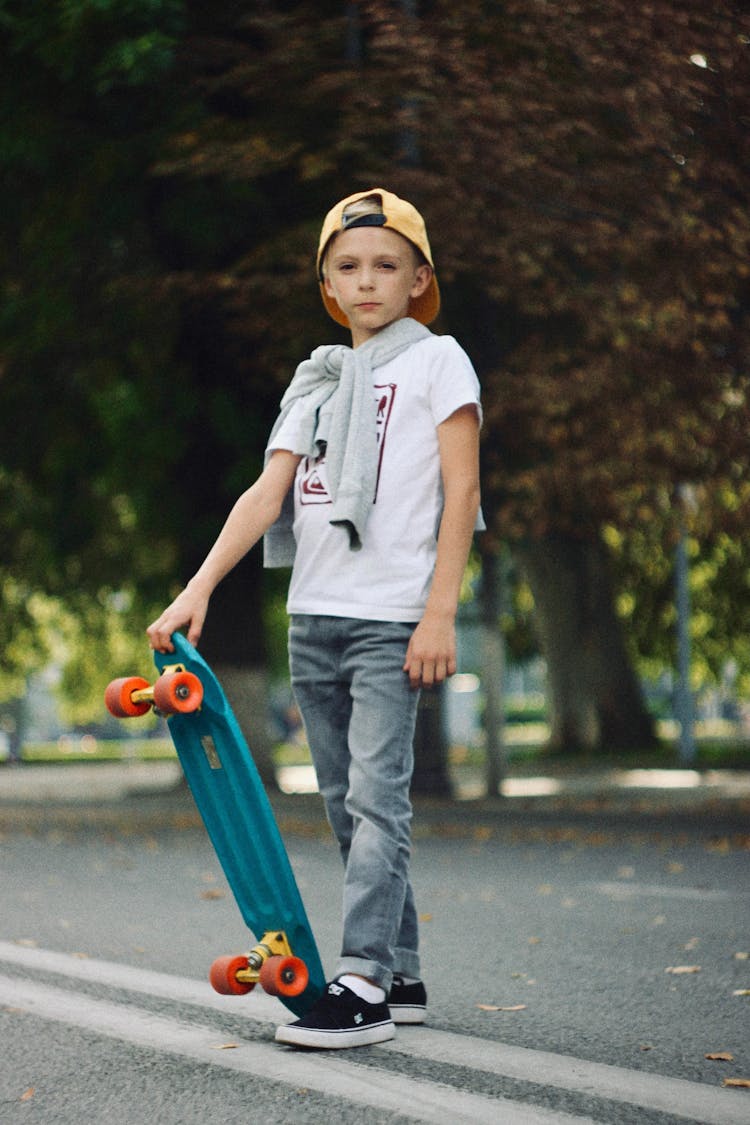 A Young Boy Holding A Skateboard