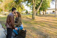 一对恩爱的夫妇在公园长椅上，享受着被秋树环绕的温柔时刻