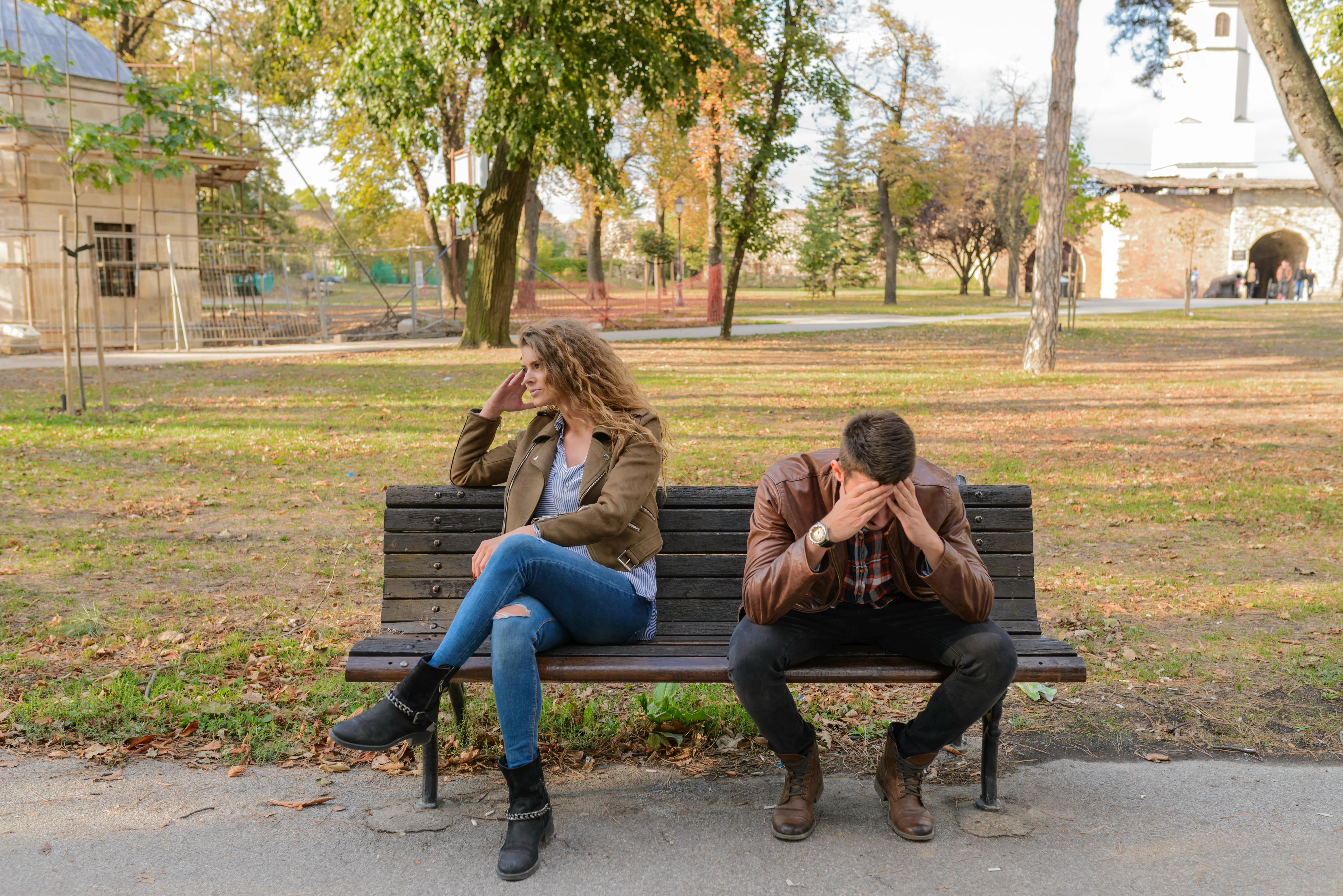 Pareja sentada en banca de madera. Fuente: Pexels