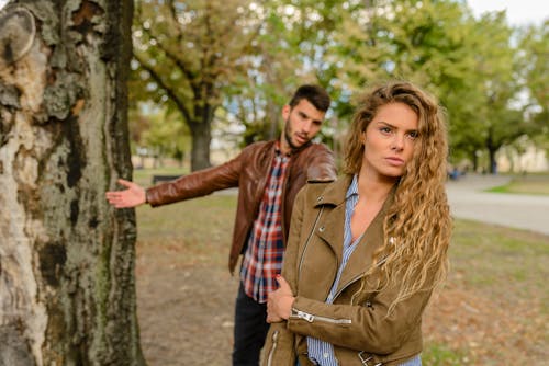 免費 女人和男人穿著棕色夾克站在樹附近 圖庫相片