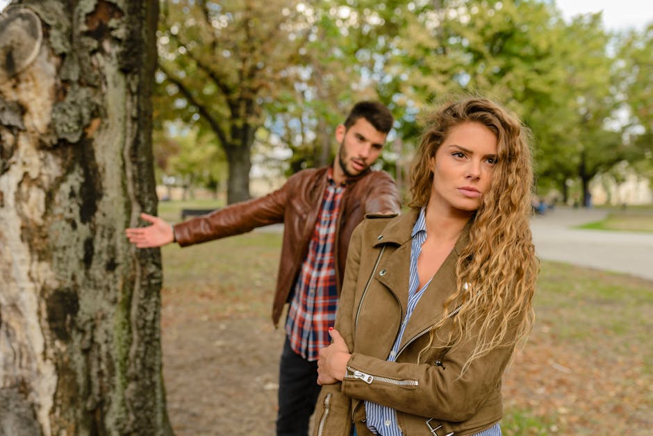 女性と男は、木の近くに立っている茶色のジャケットを身に着けている