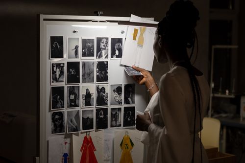 Free A fashion designer evaluating sketches and photos on a workspace board. Stock Photo