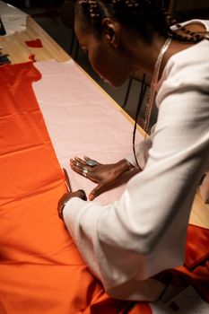 A fashion designer carefully cuts fabric patterns on a workspace, focusing on precise tailoring.