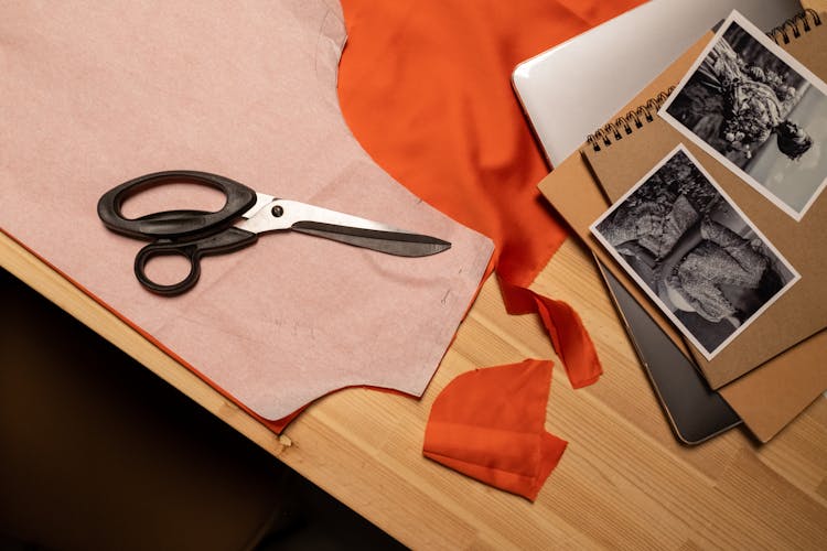 Close-up View Of Scissors, Photos And Fabrics On Table