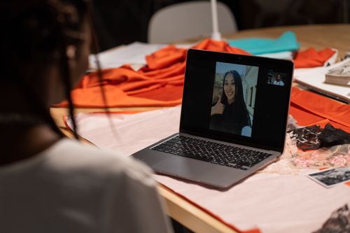 Free Fashion designer talking on a video call surrounded by fabric and design materials. Stock Photo