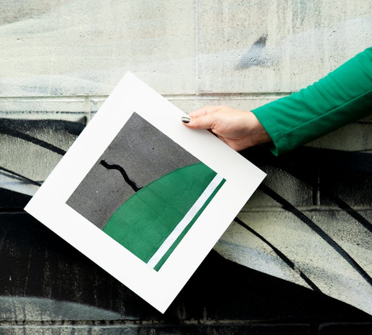 A Person Holding A Poster Near A Wall