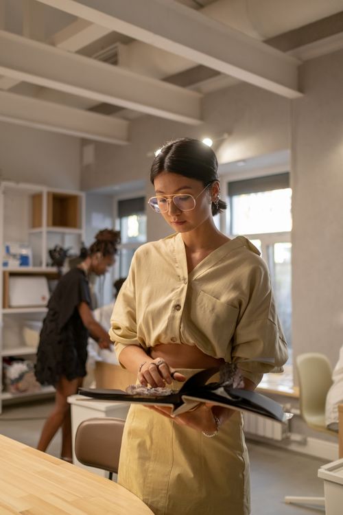 Free A focused fashion designer reviews designs in a modern, light-filled studio. Stock Photo