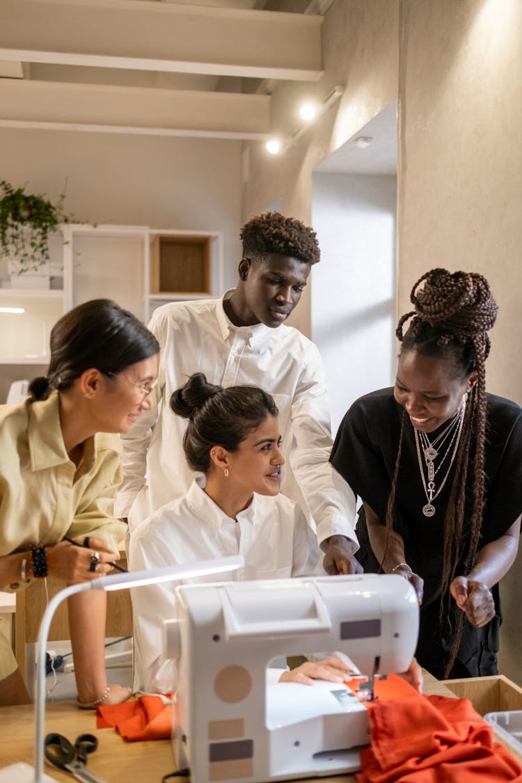 A Group Of People Sitting In Front Of A Sewing Machine 