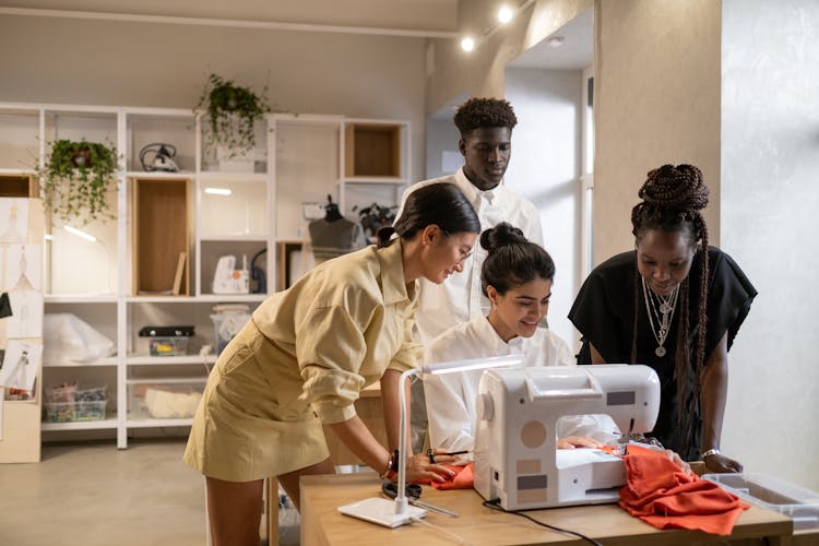 A Group Of People Having Conversation While Looking At The Sewing Machine