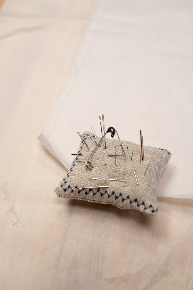 A Close Up On Pillow With Needles And Pin In It 