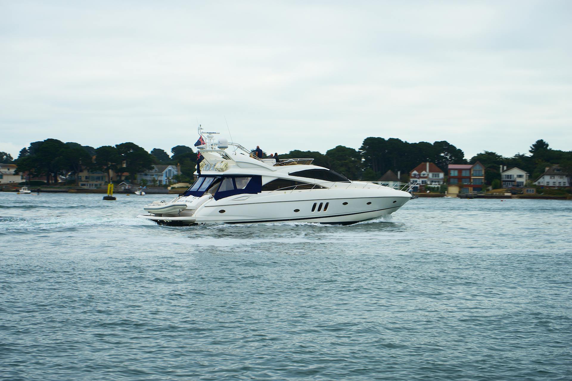 Luxurious yacht cruising on tranquil waters near Poole, England with scenic coastal backdrop.