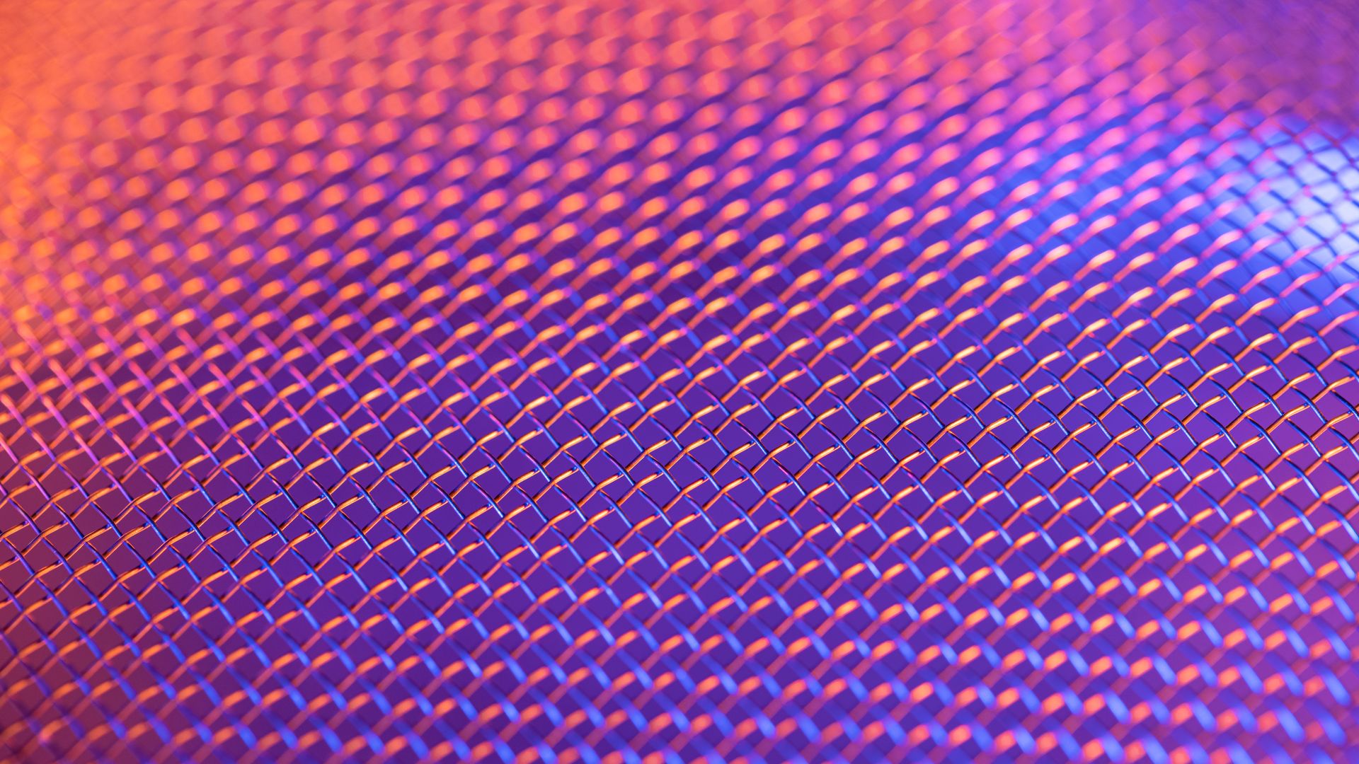 Close-up of a metallic mesh pattern with vibrant lighting creating a colorful abstract effect.
