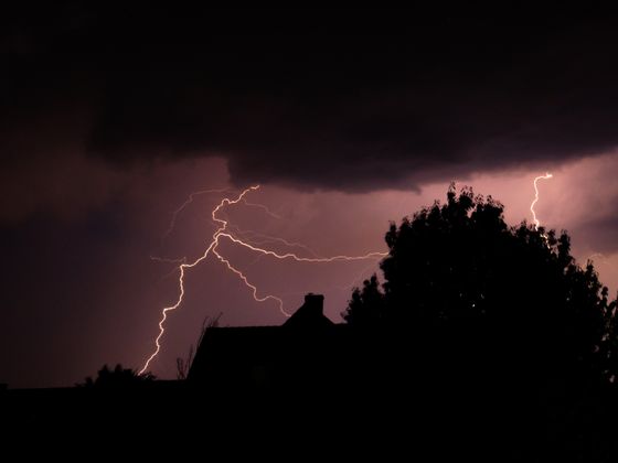 A lightning bolt over the silhouetted rooftops of a neighbourhood