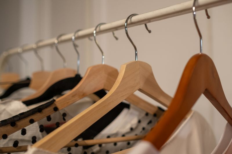 Wooden hangers holding hung and folded clothing indoors