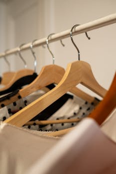 A close-up of wooden hangers displaying various stylish clothing items in a wardrobe.
